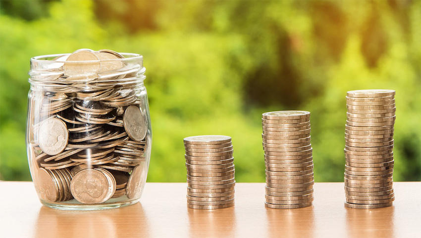 a jar of coins next to coins in stacks